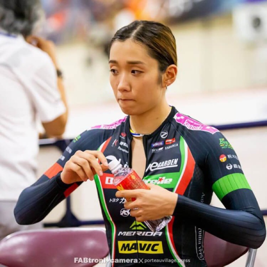 Track cyclist opening a bottle of WOX at a velodrome